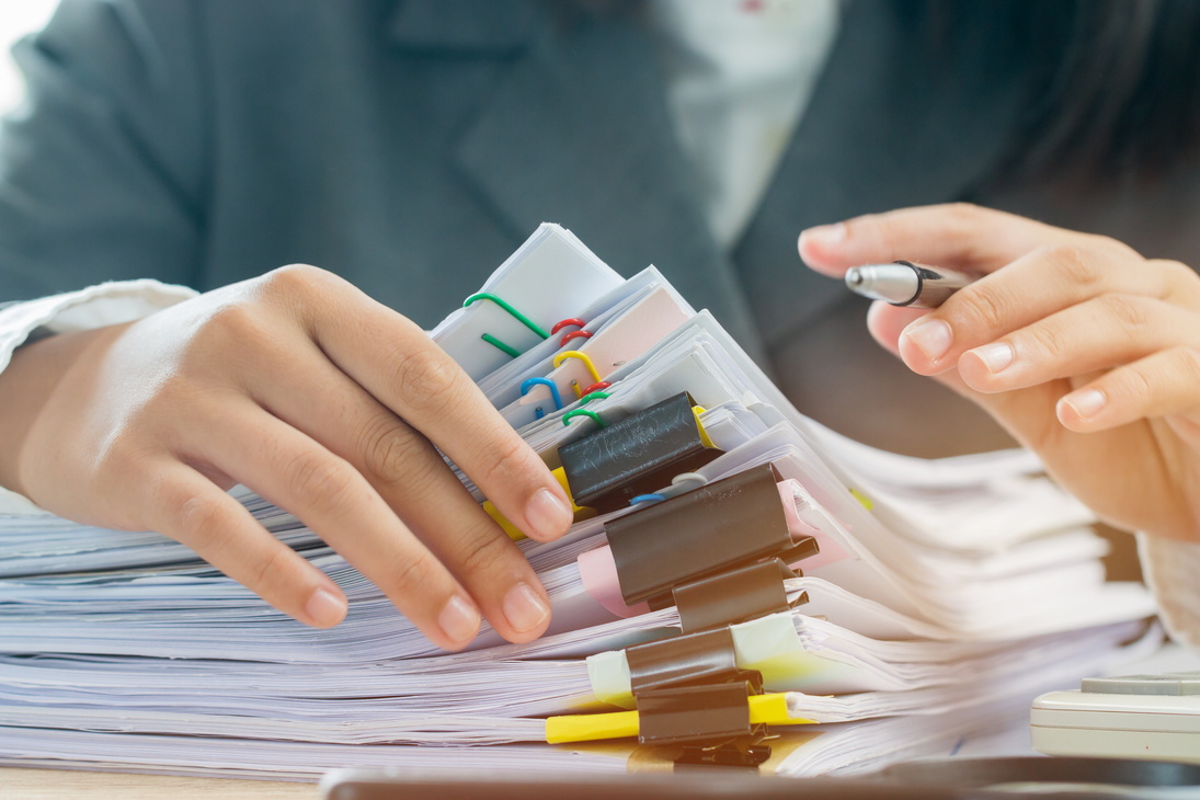 Accounting planning budget concept : Business woman offices working for arranging documents unfinished stack of document papers with pen, calculator, clip papers on busy office desk